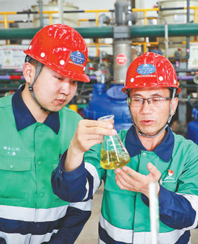 潘从明（右）在生产现场指导职工进行实验。新华社记者 马希平摄