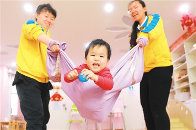 图为5月23日，红旗楼街道红北社区婴幼托育服务中心育婴师通过游戏培养孩子的身体协调能力。