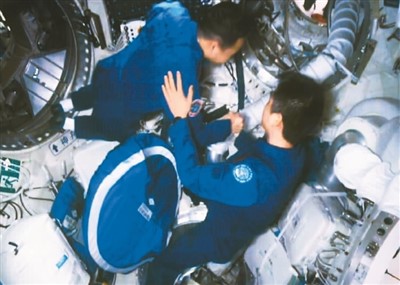 11月30日，在酒泉卫星发射中心拍摄的神舟十四号航天员陈冬（右）在天和核心舱气闸舱迎接神舟十五号航天员乘组的画面。新华社记者 郭中正摄