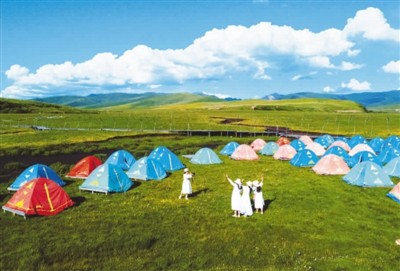 游客露营在四川省阿坝藏族羌族自治州红原县俄么塘草原花海景区，乐享夏日时光。艾加宪摄（人民图片）