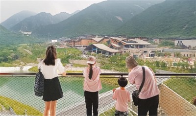 游客在观景平台上远眺延庆冬奥村全景。