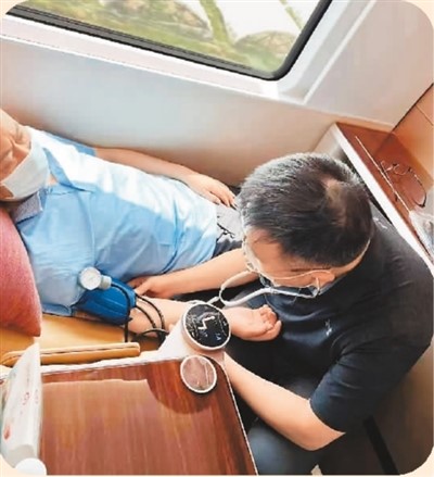 唐熠达（右）在火车上为老人测量血压。（图片来自“人民日报”微信公众号）