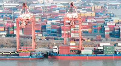 2022年12月27日，江苏省扬州港集装箱码头，货轮停在泊位上装卸集装箱。孟德龙摄（人民视觉）